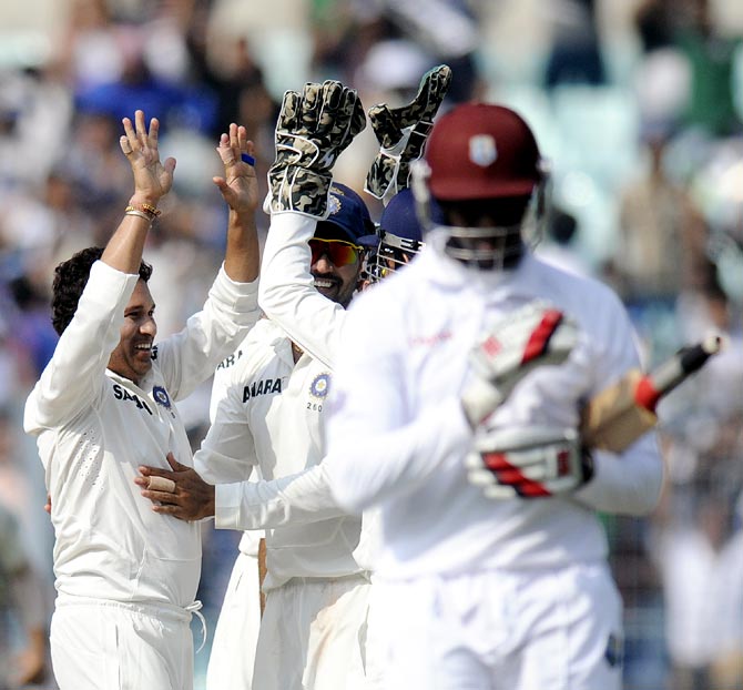Sachin Tendulkar (left) celebrates with his team mates after taking the wicket of Shane Shillingford