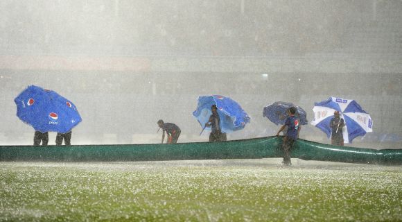Groundstaff stuggle to cover the field as heavy rain and hailstones lash the ground