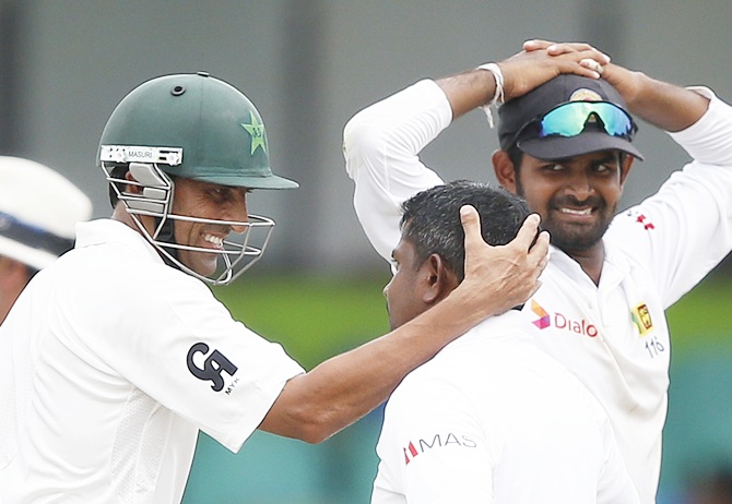 Pakistan's Younis Khan, left, talks with Sri Lanka's Rangana Herath, centre, who took his wicket as Lahiru Thirimanne looks on