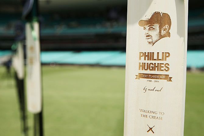 63 cricket bats with Phillip Hughes's milestones are displayed on the SCG as people gather to watch the funeral service held in Macksville