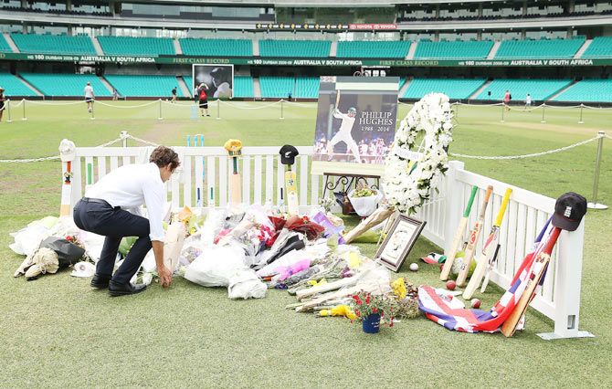 People lay flowers at the Randwick End of the SCG prior to the gathering of people to watch the funeral service of Phillip Hughes