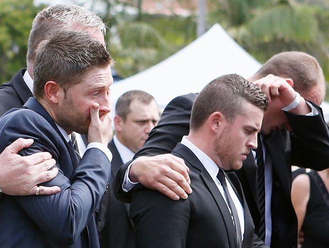 Australian cricket team captain Michael Clarke, left, is comforted as he cries with other   mourners