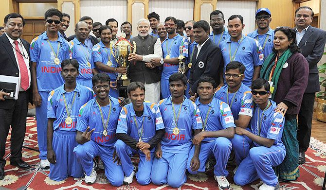 Prime Minister Narendra Modi holds up the trophy as he poses with the Indian Blind World Cup-Winning team