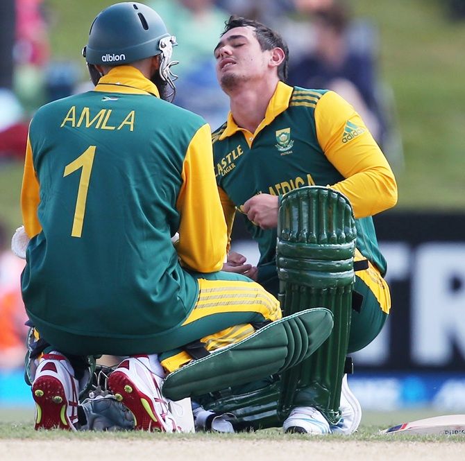 Quinton de Kock of South Africa is attended to by teammate Hashim Amla