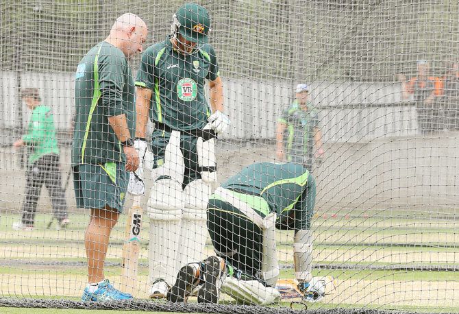 Darren Lehmann and Joe Burns of Australia check on Mitchell Starc after he falls to the ground following a blow to the knee