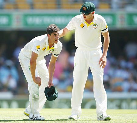 Peter Siddle of Australia checks on teammate Mitchell Starc of Australia on Day 1 of the 2nd Test match against India at The Gabba in Brisbane