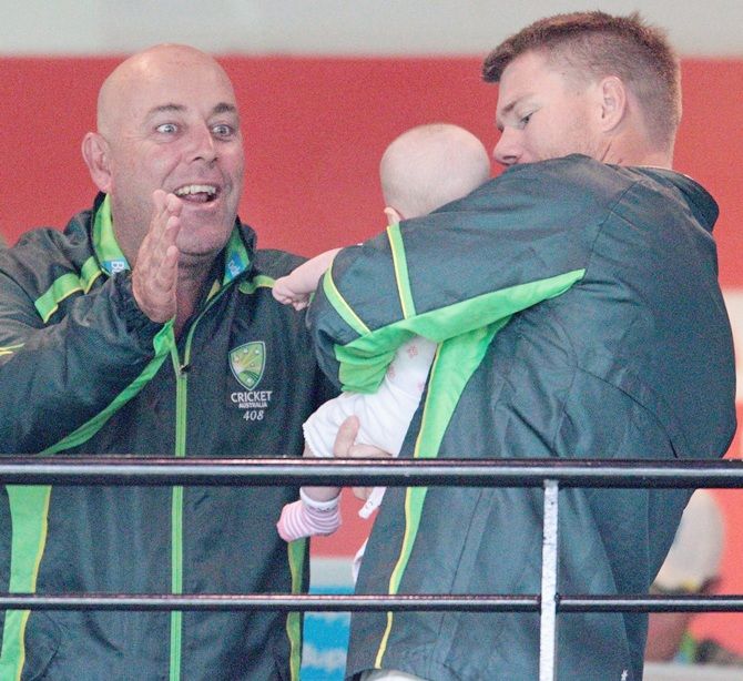 Darren Lehmann, left, the coach of Australia and David Warner of Australia play with Warner's daughter Ivy Mae during a rain delay