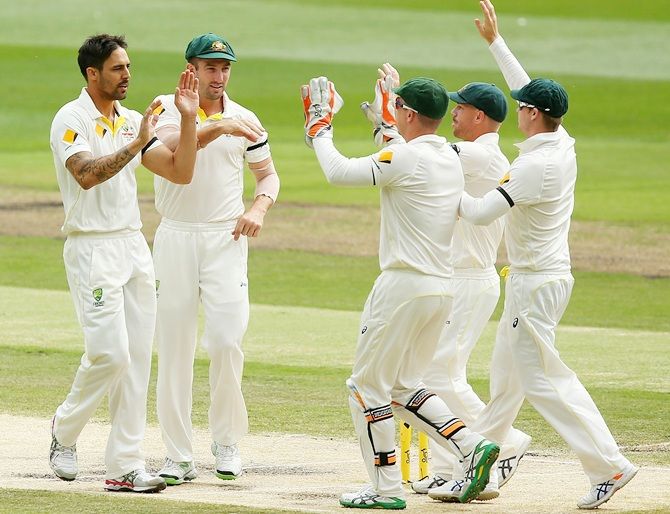 Mitchell Johnson of Australia celebrates with team mates after dismissing Umesh Yadav of India