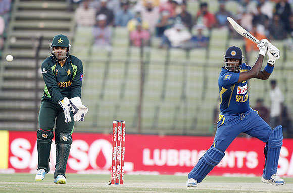 Sri Lanka's captain Angelo Mathews plays a shot as Pakistan's wicketkeeper Umar Akmal (L) watches during their One-day International at the 2014 Asia Cup in Fatullah on Tuesday