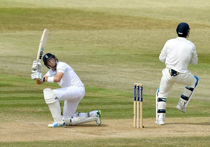Joe Root improvises to pick up some runs as he is watched by Mahendra Singh Dhoni
