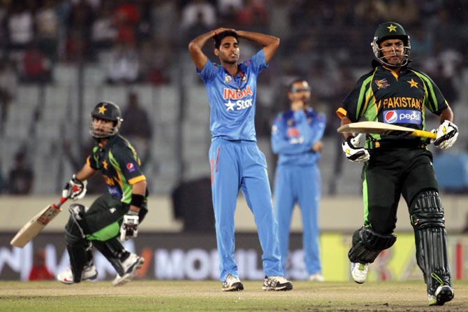 India pacer Bhuvneshwar Kumar, centre, reacts as Pakistan's Ahmed Shahzad (left) and Sharjeel Khan run between the wickets