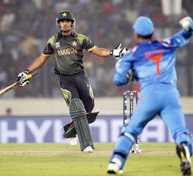 Pakistan's captain Mohammad Hafeez, left,  tries to take a run as India's captain and wicketkeeper MS Dhoni throws a ball