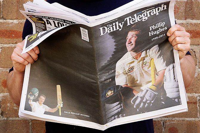 A man holds The Daily Telegraph newspaper showing headlines surrounding the death of Phillip Hughes in Sydney on Friday