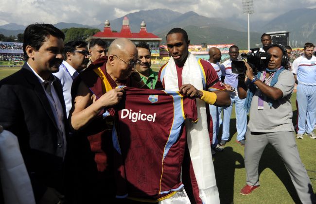 His Holiness the 14th Dalai Lama is presented with a West Indies team jersey by Dwayne Bravo captain of West Indies before the start of the 4th One Day International in Dharamsala in October 2014