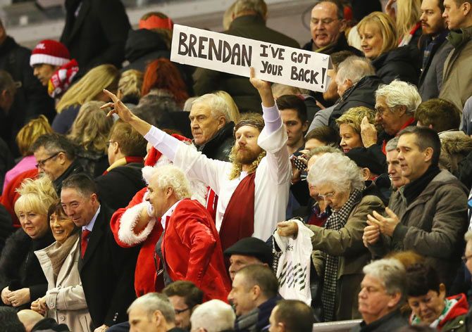 Fans dressed as Santa Claus and Jesus display a sign for Liverpool manager Brendan Rodgers