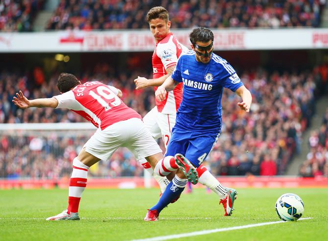 Chelsea's Cesc Fabregas is challenged by Arsenal's Santi Cazorla and Olivier Giroud