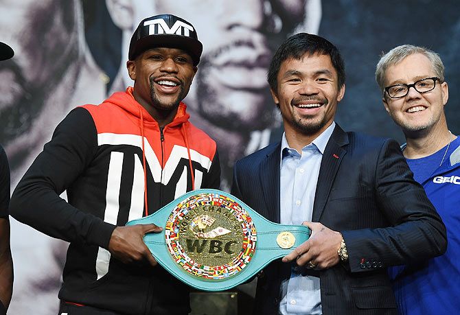 WBC/WBA welterweight champion Floyd Mayweather Jr. and WBO welterweight champion Manny Pacquiao pose with a WBC championship belt as Pacquiao's trainer Freddie Roach looks on during a news conference at the KA Theatre at MGM Grand Hotel & Casino in Las Vegas on Wednesday