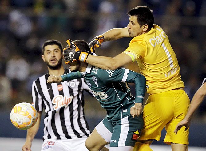 Chile's Santiago Wanderers' Carlos Gonzalez (centre) fights for the ball with Paraguayan club Libertad's Rodrigo Munoz (right) and Pedro Benitez (left) during their Copa Sudamericana match at the Nicolas Leoz stadium in Asuncion on Tuesday, August 18
