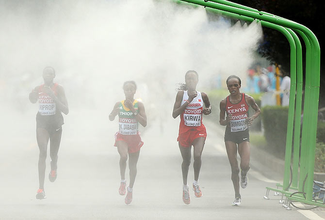 Kenya's Helah Kiprop, Bahrain's Eunice Jepkirui Kirwa and Ethiopia's Mare Dibaba enter a cooling station during the Women's Marathon final on Sunday