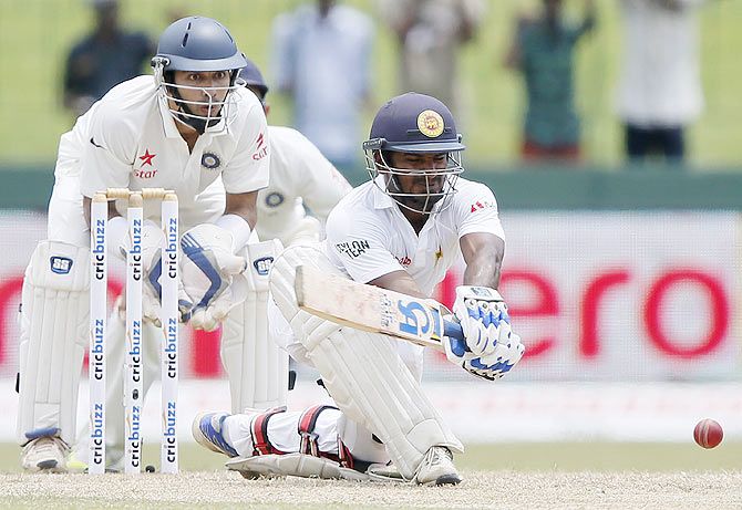 Sri Lanka's Kusal Perera (front) hits a boundary as India's wicketkeeper Naman Ojha watches