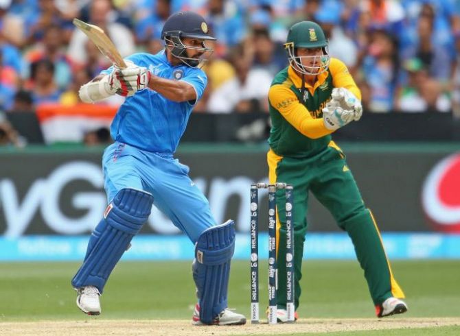 Shikhar Dhawan of India hits a boundary as wicketkeeper Quinton de Kock of South Africa looks on