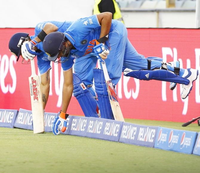 Virat Kohli, left, and Rohit Sharma touch the grass in synchronisation before they step back out onto the field to resume their innings. David Gray/Reuters 