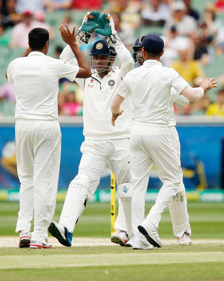Mahendra Singh Dhoni celebrates the wicket of David Warner with teammates