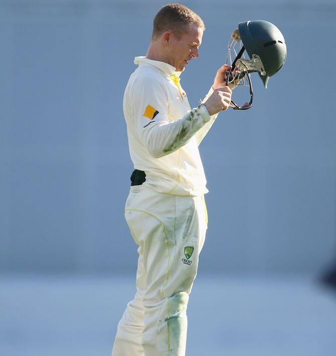 Chris Rogers of Australia inspects his helmet after he was hit fielding during The Gabba Test match