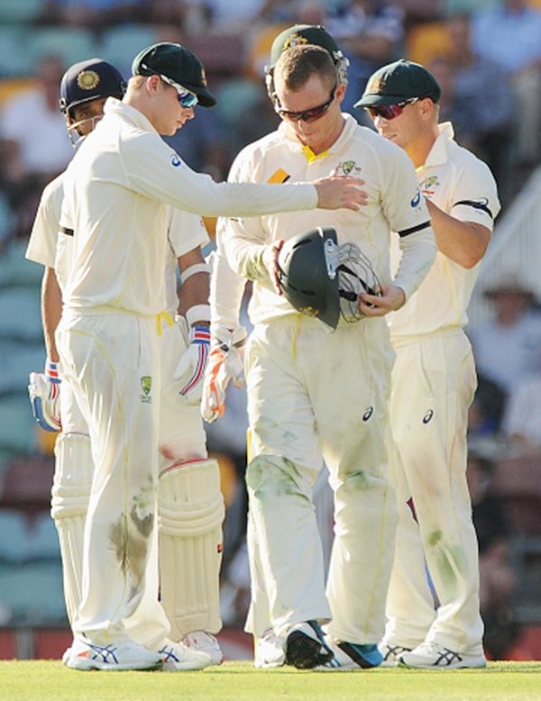Chris Rogers of Australia with his teammates inspects his helmet