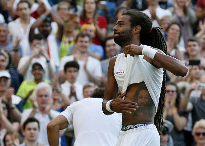 Dustin Brown pats a tattoo of his father on his stomach after winning his match against Rafael Nadal