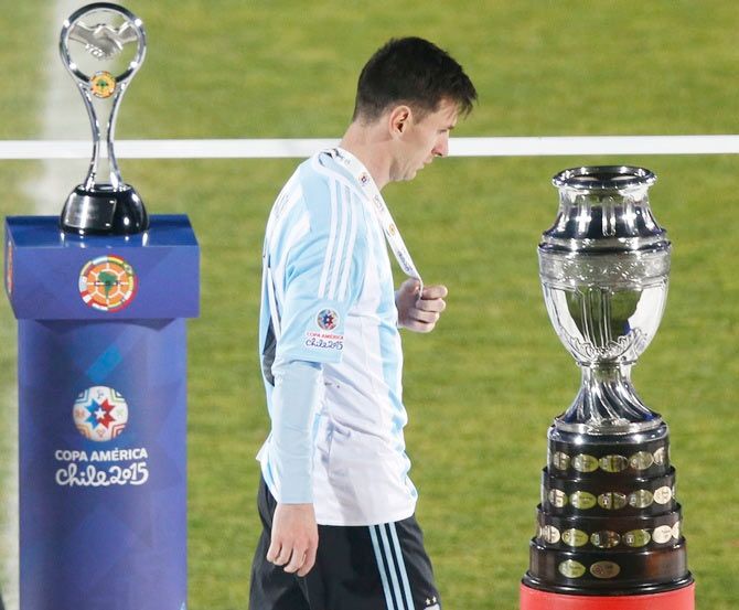 Argentina's Lionel Messi walks with his silver medal past the Copa America trophy after losing the Copa America final to Chile on July 4