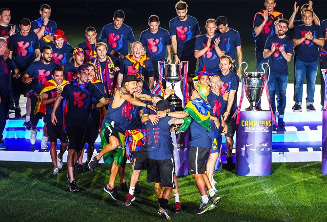 Barcelona players are ecstatic as they celebrate with the La Liga, Copa del Rey and Champions League trophies at the Camp Nou Stadium, following their victory parade