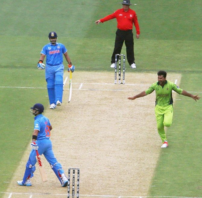 India's batsman Virat Kohli, left, walks off the pitch upon his dismissal as Pakistan bowler   Sohail Khan celebrates