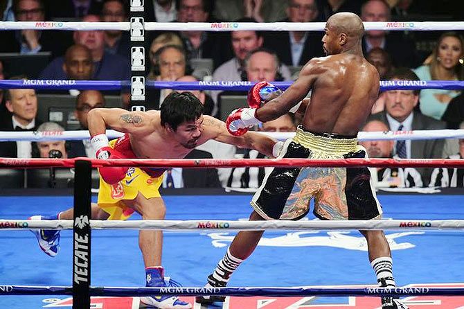 Manny Pacquiao lands a punch against Floyd Mayweather, Jr. (right)