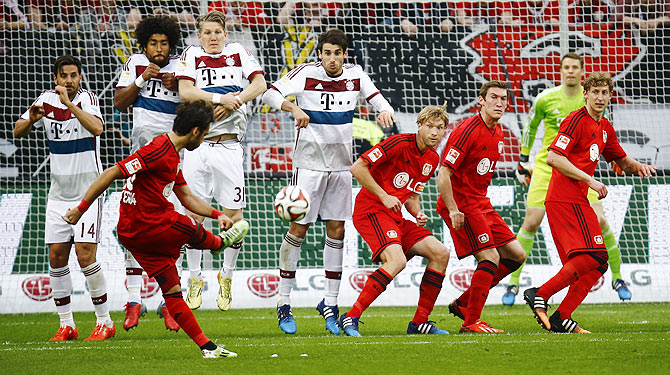 Bayer Leverkusen's Hakan Calhanoglu (centre) shoots to score a goal on freekick against Bayern Munich during their Bundesliga match in Leverkusen on Saturday