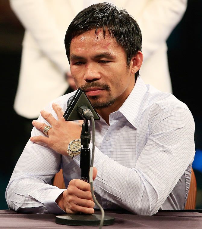 Manny Pacquiao points to his right shoulder during the post-fight news conference after losing to Floyd Mayweather Jr.