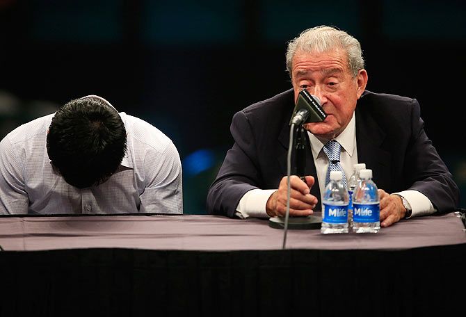 Manny Pacquiao lowers his head as he sits with Bob Arum of Top Rank during the post-fight news conference on Saturday