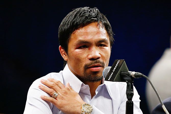 Manny Pacquiao points to his right shoulder during the post-fight news conference after losing to Floyd Mayweather Jr. in their welterweight unification championship bout at MGM Grand Garden Arena in Las Vegas, Nevada, on Saturday