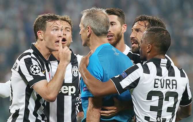 Juventus' Stephan Lichtsteiner, Claudio Marchisio, Andrea Pirlo and Patrice Evra surround referee Martin Atkinson after a penalty is awarded as Real Madrid's Sergio Ramos looks on