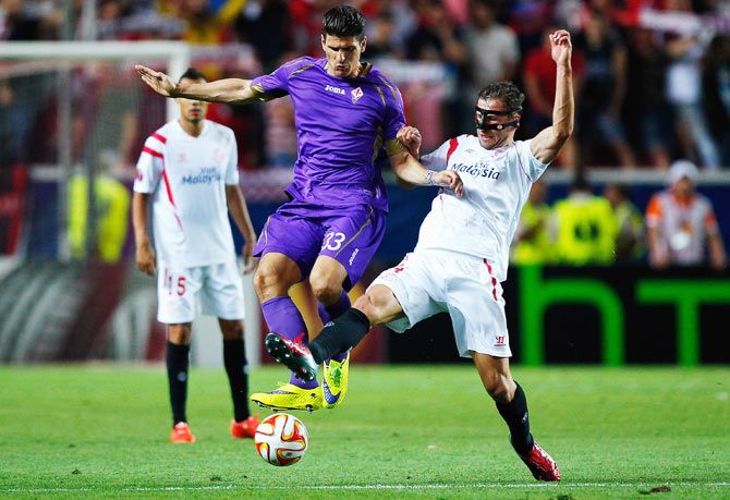 Mario Gomez of Fiorentina is tackled by Grzegorz Krychowiak of Sevilla