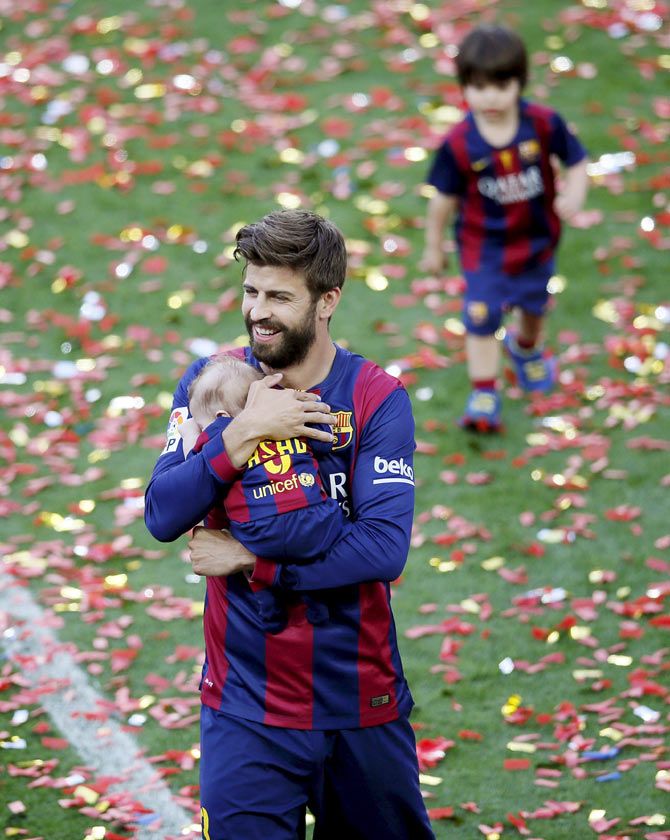 Barcelona's player Gerard Pique holds his son Sasha, followed by his older son Milan, during victory celebrations