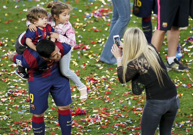 Barcelona's Luis Suarez (left) holds his children Delfina and Benjamin while his wife Sofia Balbi takes a picture during celebrations after winning the La Liga crown on May 24