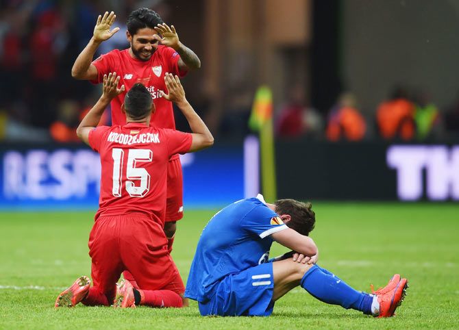 Sevilla's Benoit Tremoulinas celebrates with teammate Timothee Kolodziejczak as Dnipro's Yevhen Seleznyov sits dejected after their UEFA Europa League final