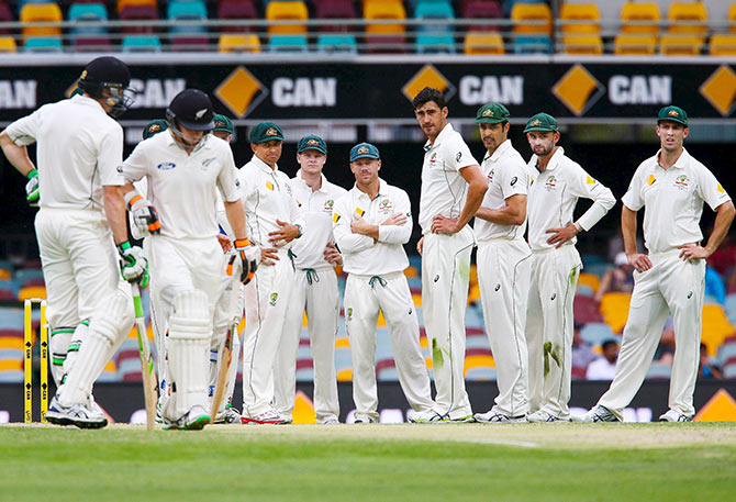 Australian players wait to see whether the New Zealand batsmen will challenge a decision 