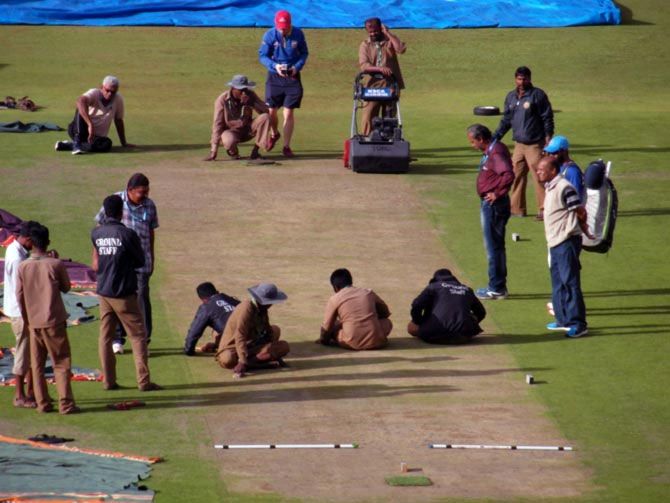 A file photo of ground staff working on the Bengaluru pitch