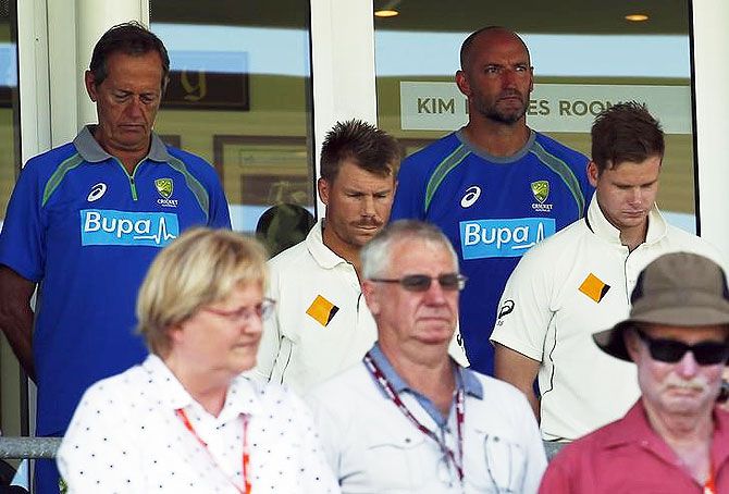 Australian team captain Steve Smith (right) and teammate David Warner (centre) bow their heads with team officials and members of the public, as they pay tribute to those killed in the Paris attacks before the start of the second day's play