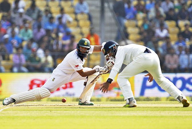 South Africa's captain Hashim Amla (left) plays a shot as India's Cheteshwar Pujara watches during the third day of their third Test cricket match in Nagpur, on Friday