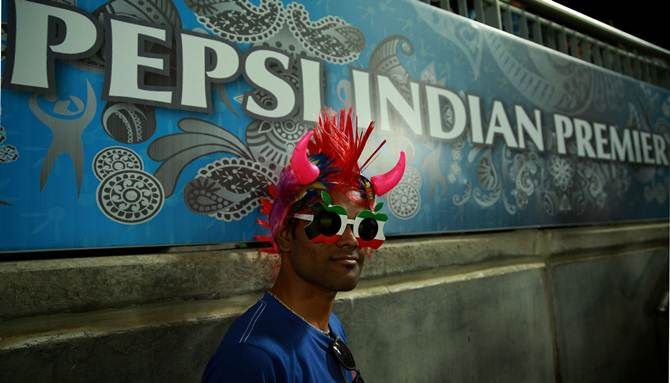 A fan poses in fron of a banner of the main IPL sponsor