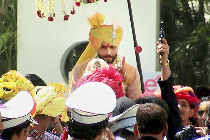 A reveller (left) fires shots in the air at Jadeja's wedding procession
