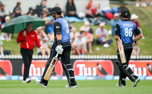 Ross Taylor (center) and Henry Nicholls (right) of New Zealand leave the field 